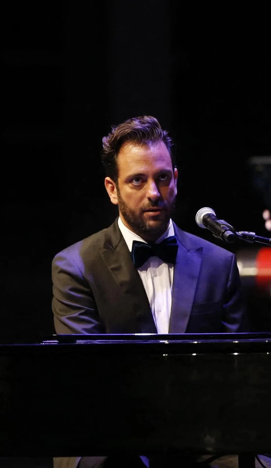 Front view of Guy Manoukian while his playing the piano, looking up