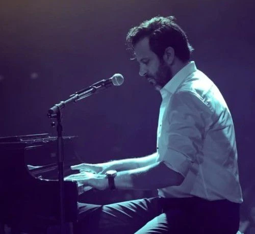 Side view of Guy Manoukian while his playing the piano, looking down on the pianko keys